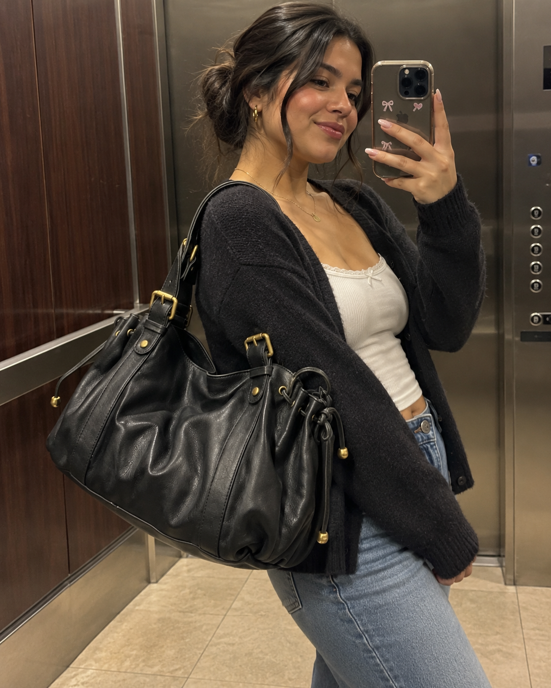 The Valen Hobo in Classic Black styled with a cream top and dark cardigan in a mirror portrait.
